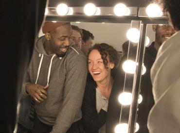 Two LAMDA students looking into a mirror in The Sainsbury Theatre's dressing room and laughing