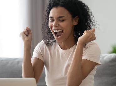 A LAMDA learner celebrates in front of a laptop