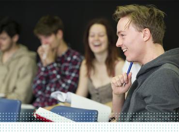 A LAMDA learner laughs holding a script