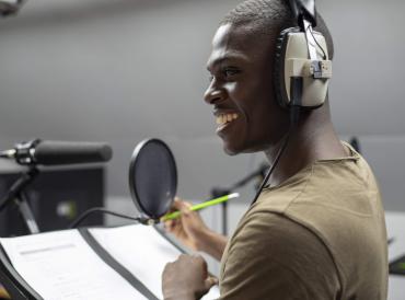 Smiling student in recording booth with headphones