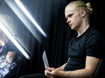 Man sitting with script, light strips in the background
