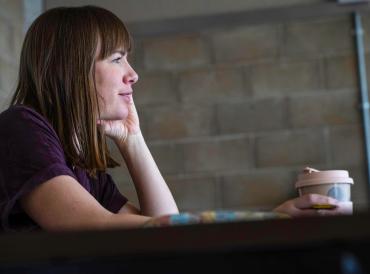 Director Elly Green sat at a desk in rehearsals for New Labour with a takeaway beverage cup