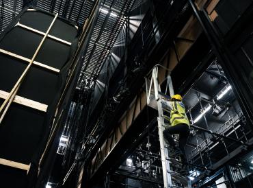 Production & Technical Arts student on a ladder