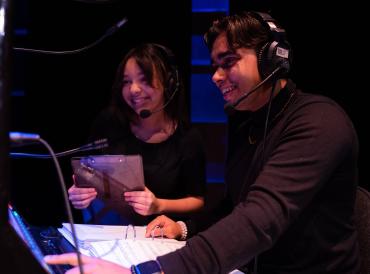 Photo of two LAMDA students smiling at a prompt desk