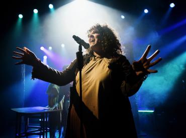 Photograph of musical theatre student on stage behind a microphone