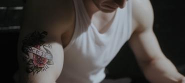 A tattoo on the bicep of a young man, depicting the name 'Jackie'