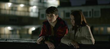 Two young adults talk outside a block of flats