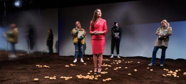 A group of people stand in a field of potatoes