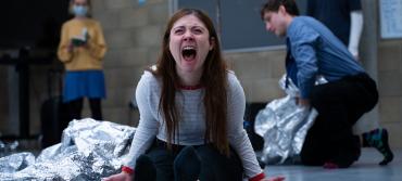 A young woman screams while a man gathers silver blankets 