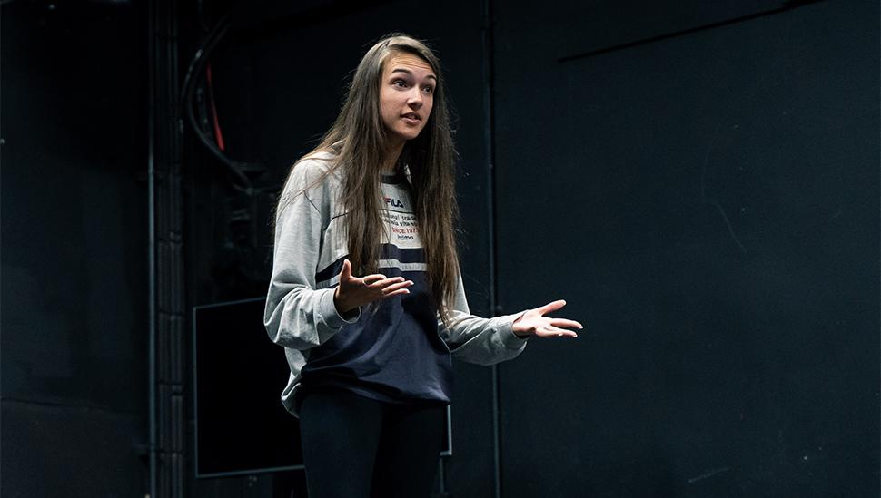 A LAMDA student stands with hands open