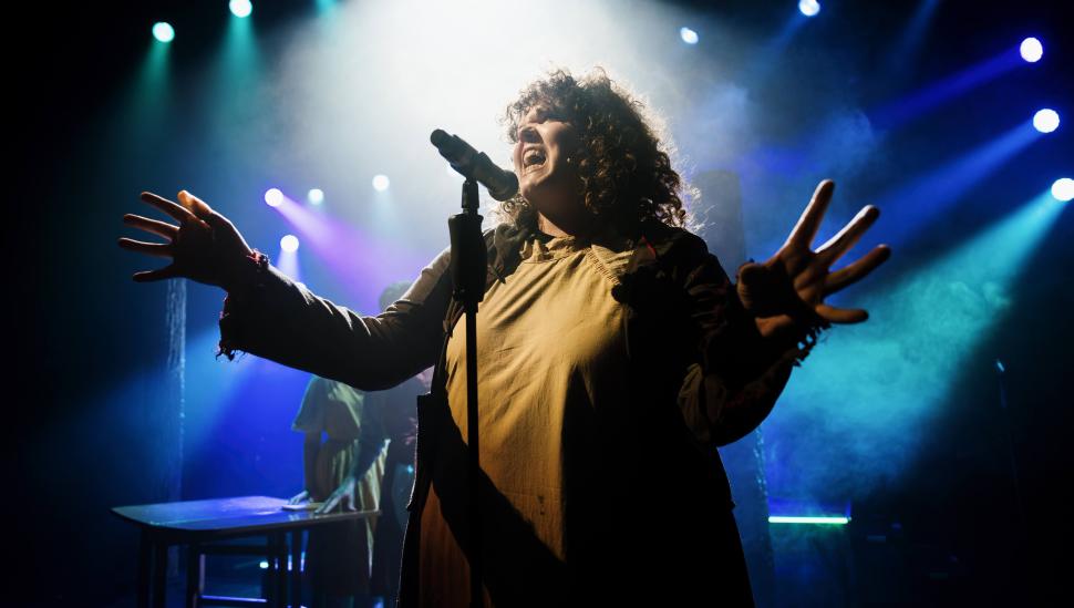 Photograph of musical theatre student on stage behind a microphone