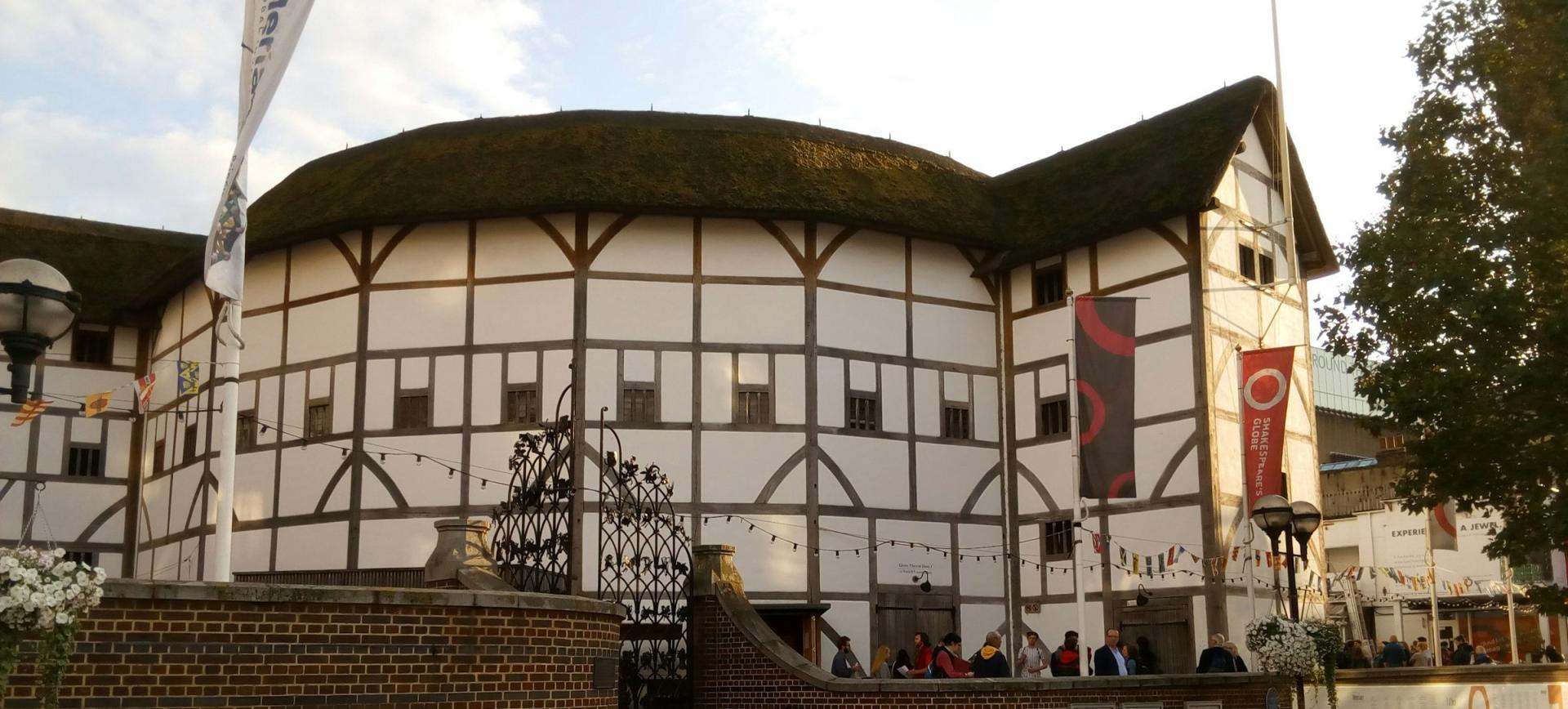 Shakespeare's Globe theatre in London, a round timber-framed building with a thatched roof and banners outside