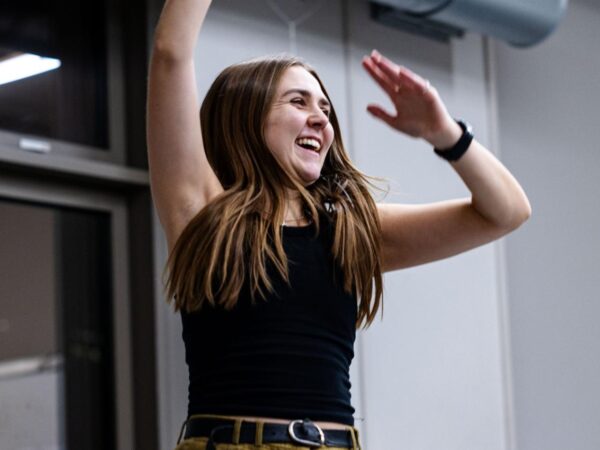 Woman laughing with arms raised, dancing joyfully indoors