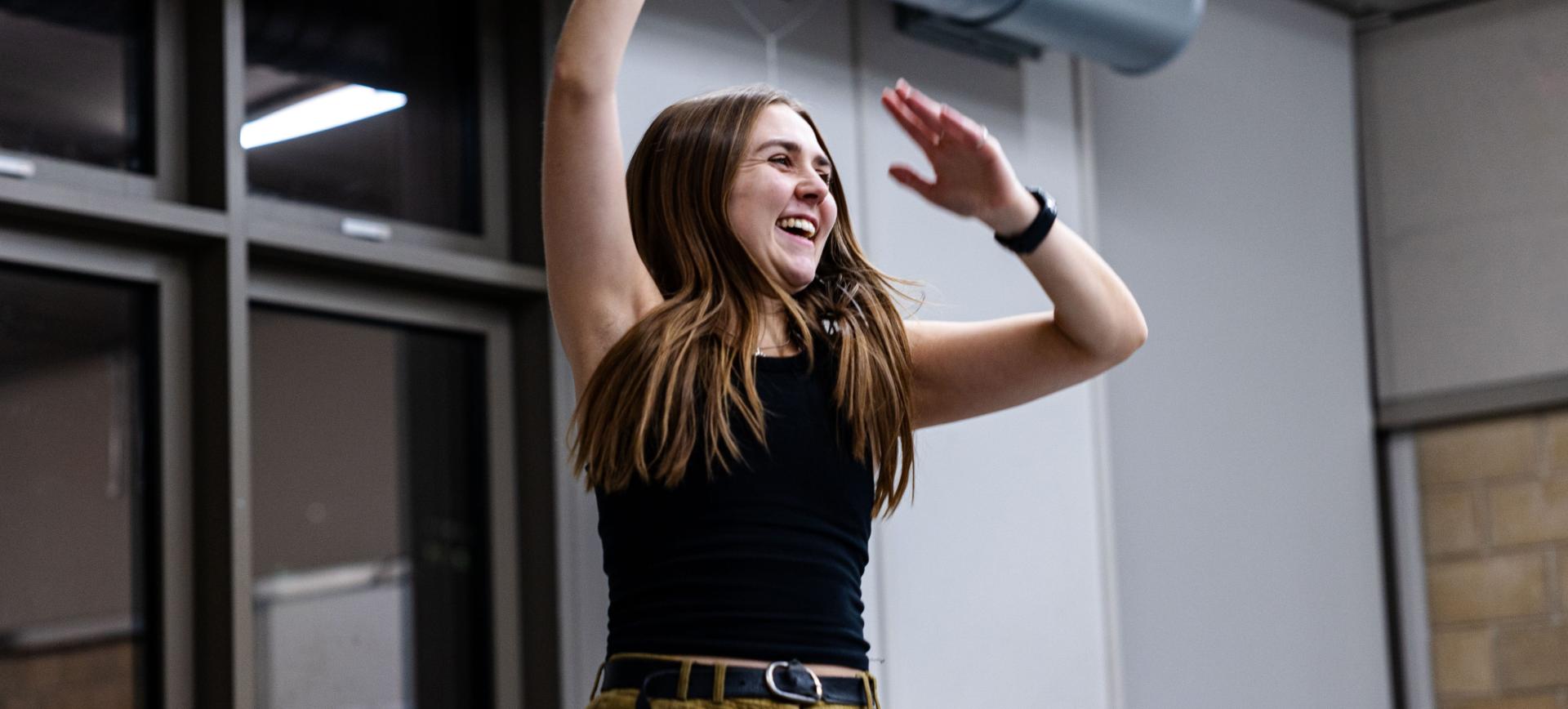Woman laughing with arms raised, dancing joyfully indoors