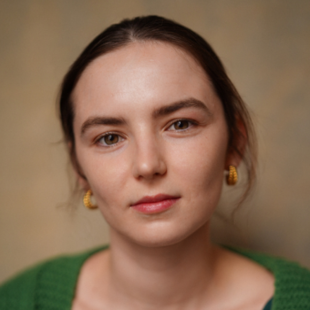 Close-up portrait of a young woman with dark hair pulled back, wearing gold earrings and a green top