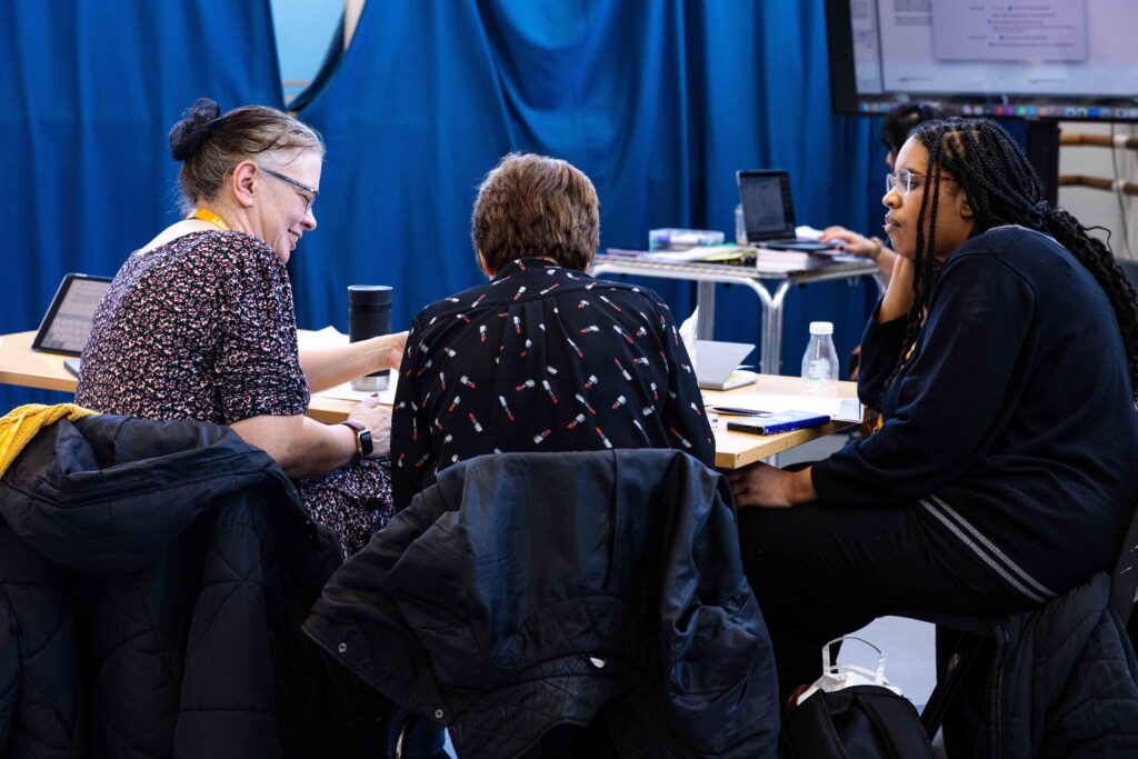 A group of three teachers talk during a teacher training course.