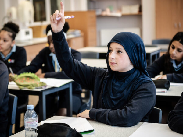 A learner raises their hand in class.