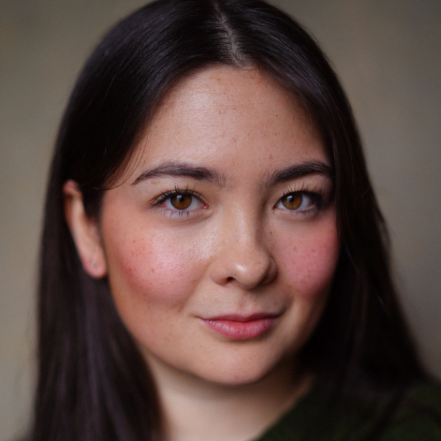 Close-up portrait of a young woman with long dark hair, smiling gently at the camera