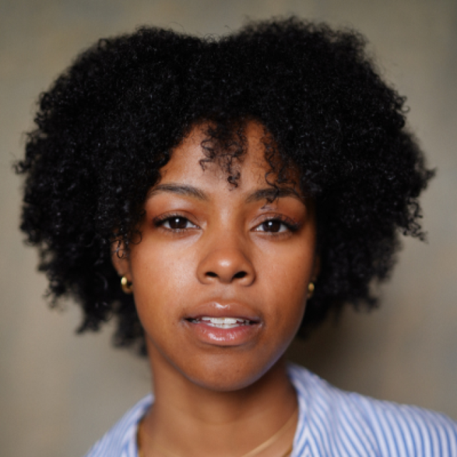 Close-up portrait of a woman with curly natural hair, wearing a striped shirt, looking directly at the camera