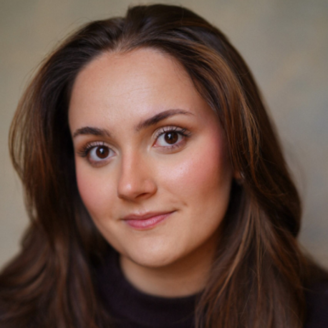 Portrait of a woman with long brown hair, smiling gently at the camera