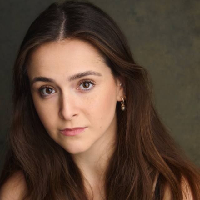 Close-up portrait of a young woman with long brown hair, looking directly at the camera
