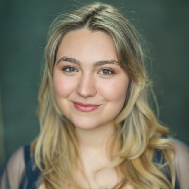 Portrait of a young woman with wavy blonde hair, smiling against a dark green background