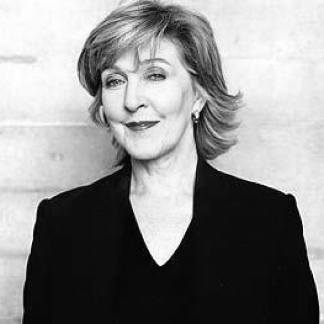 Black-and-white portrait of a woman with shoulder-length hair, wearing a dark jacket, smiling slightly