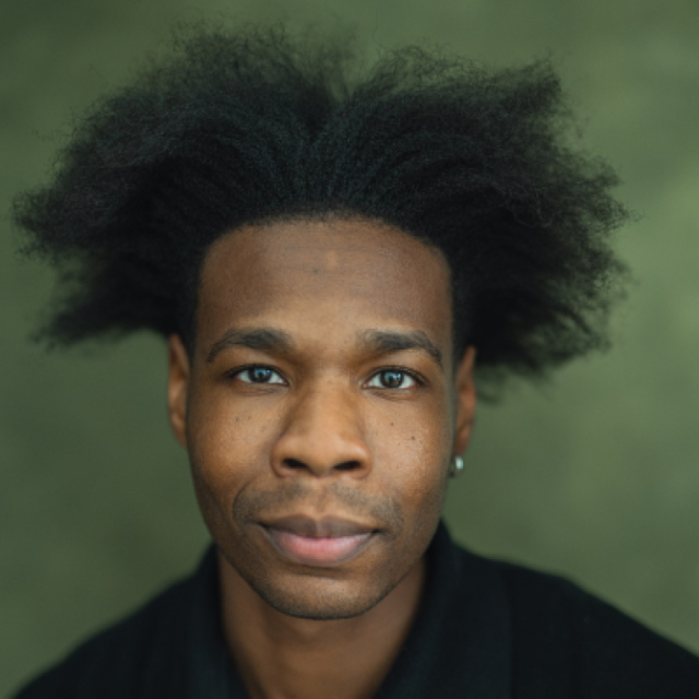 Close-up portrait of a man with voluminous curly hair, looking directly at the camera