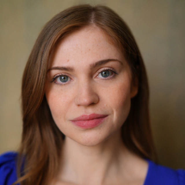 Portrait of a young woman with long auburn hair and blue eyes, wearing a blue top