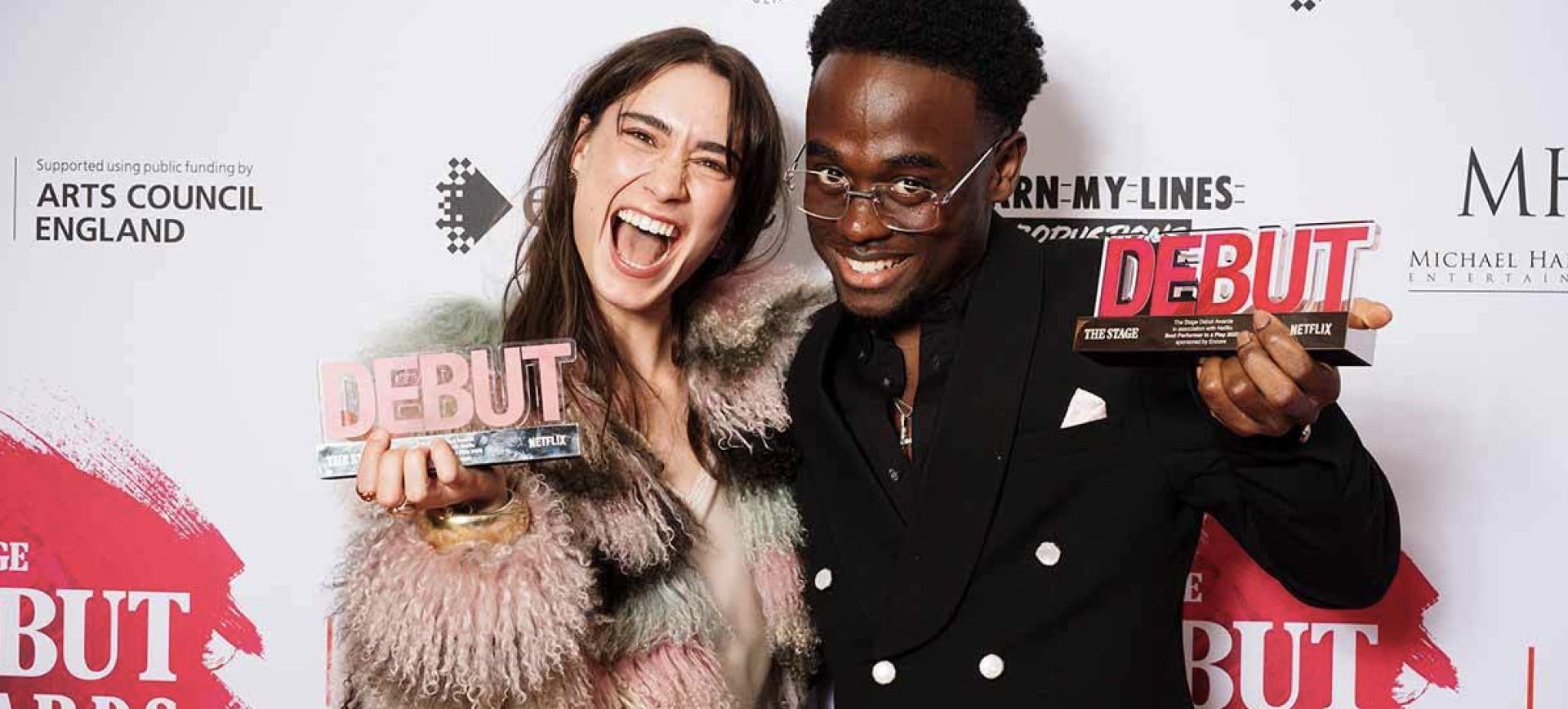 Two winners laughing and holding their Stage Debut Awards trophies at the ceremony