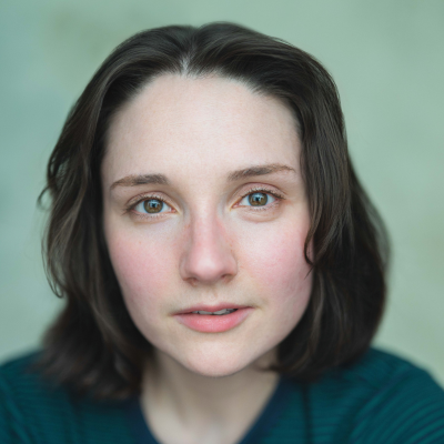 Head-and-shoulders portrait of a young woman with shoulder-length brown hair, looking directly at the camera