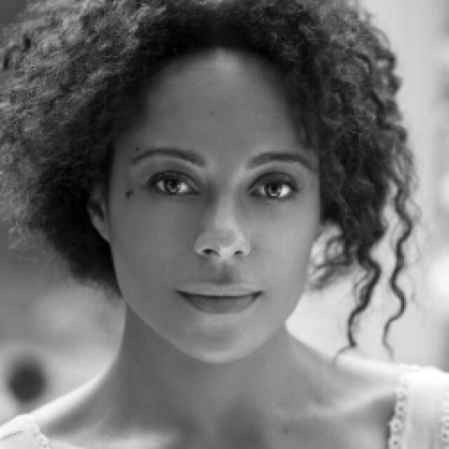 Black and white portrait of a woman with curly hair looking directly at the camera