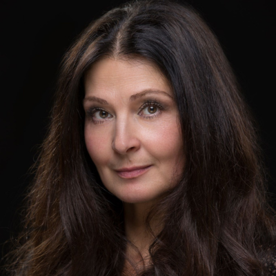 Portrait of a woman with long dark wavy hair against a black background