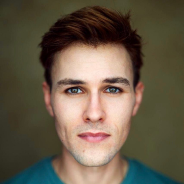 Portrait of a young man with brown hair, looking directly at the camera, wearing a teal top