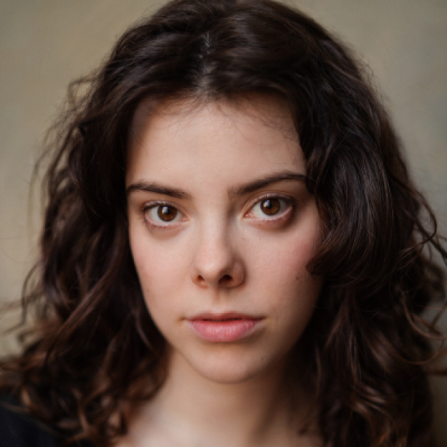 Close-up portrait of a young woman with curly brown hair and a neutral expression, looking directly at the camera
