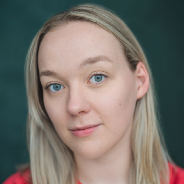Close-up portrait of a woman with blonde hair and blue eyes, wearing a red top, against a dark green background