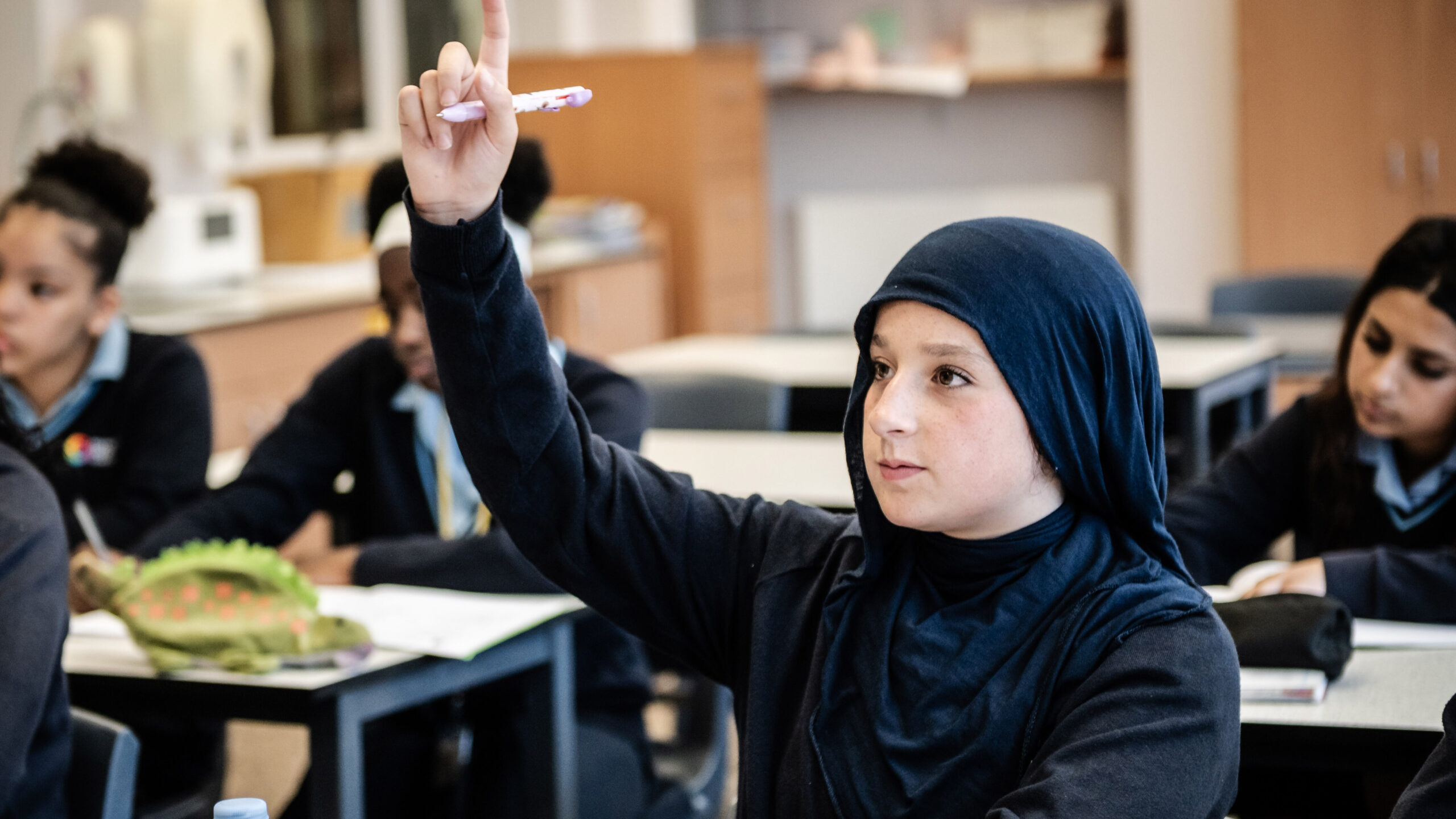 A learner raises their hand in class.