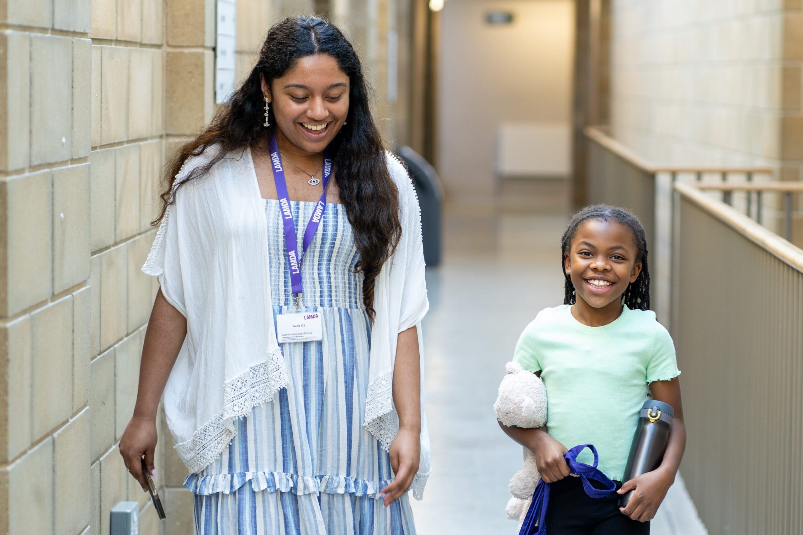 A learner and Exams steward walk down the corridor at LAMDA