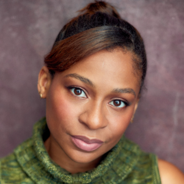 Close-up portrait of a woman with her hair tied up, wearing a green knitted top