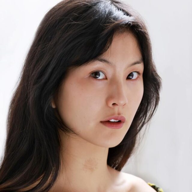 Close-up portrait of a young woman with long dark hair, looking directly at the camera