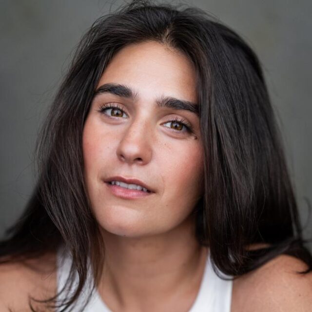 Close-up portrait of a woman with long dark hair and brown eyes, looking directly at the camera