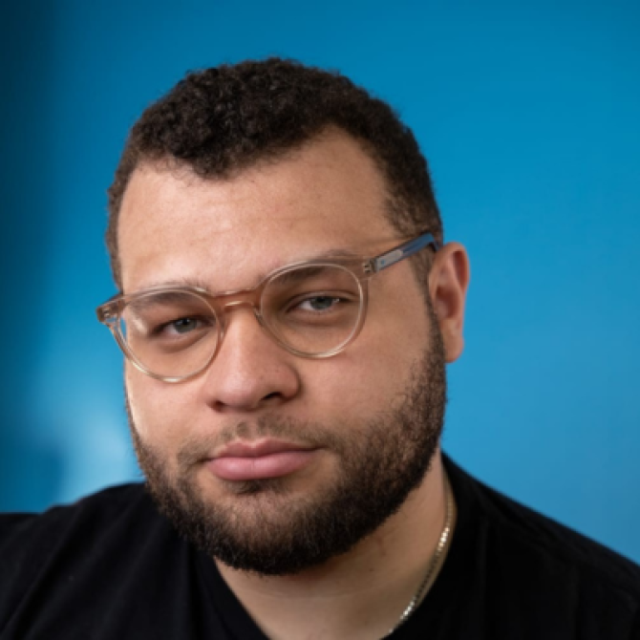 Portrait of a man with a beard and glasses against a blue background