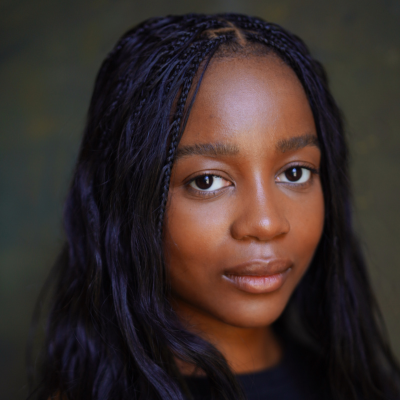 Close-up portrait of a young woman with braided hair, looking directly at the camera