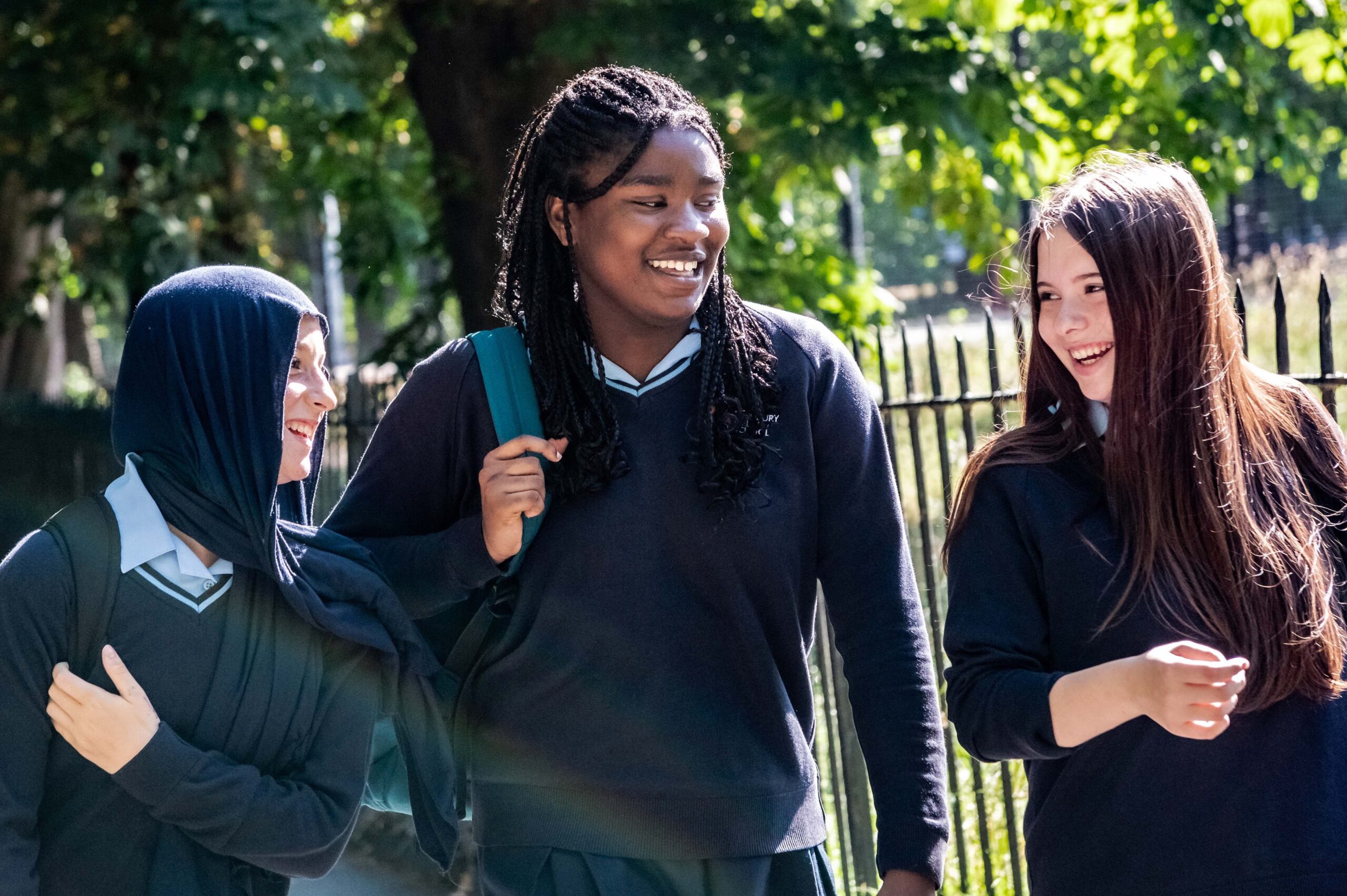 Three learners talk as they walk outside
