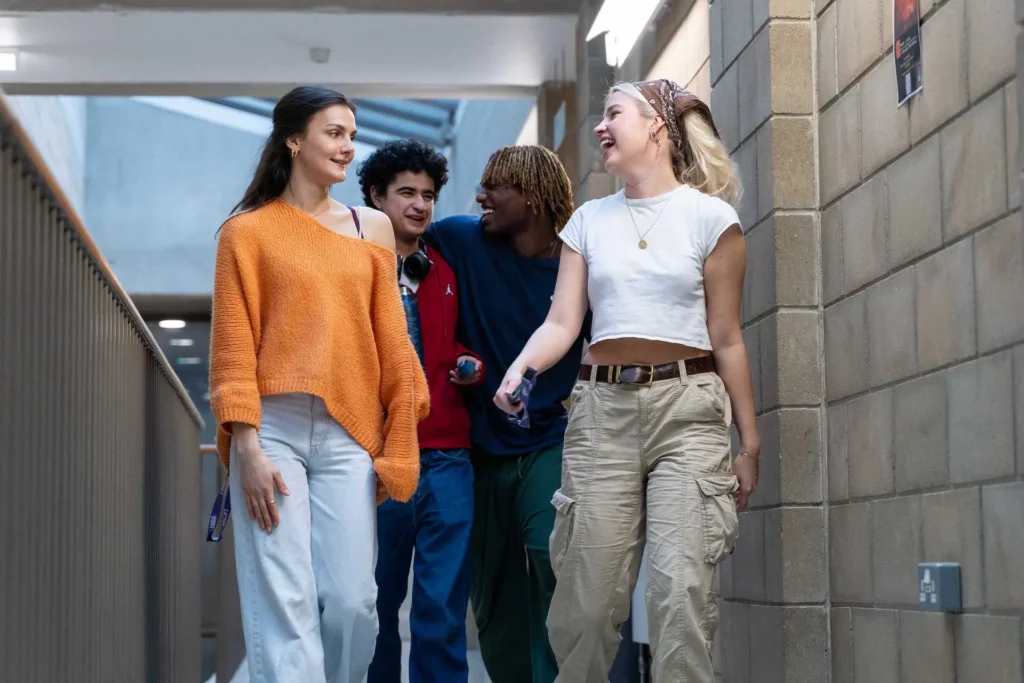 Four students laughing together while walking through a covered walkway on campus