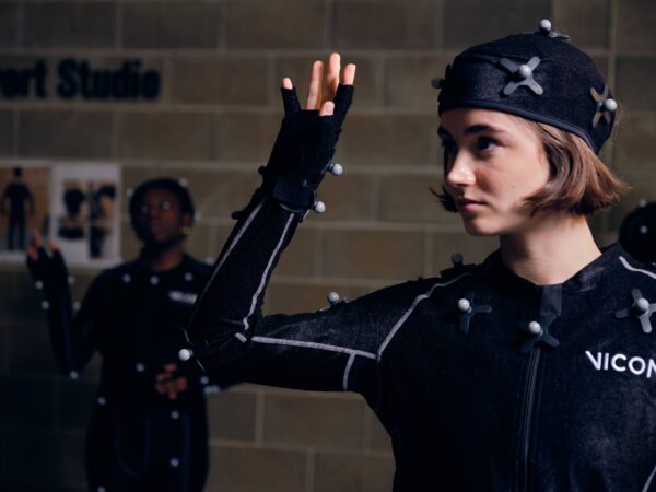 A woman in a black motion capture suit raises their right hand